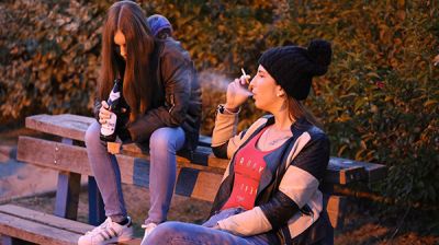 Jugendliche auf einer Bank und rauchen / trinken Alkohol